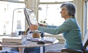 Older woman adjusting ergonomic monitor.