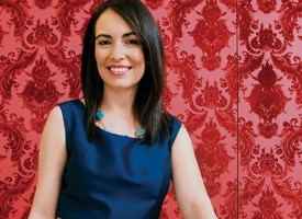 Woman in front of red patterned wallpaper