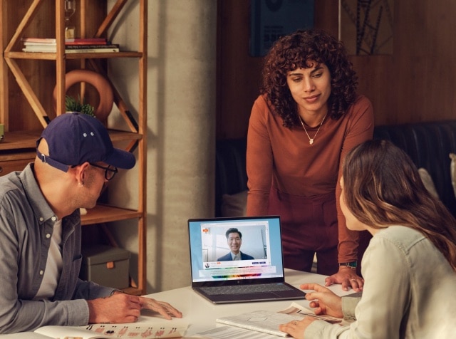 Woman showing a video on an HP laptop to her co-workers