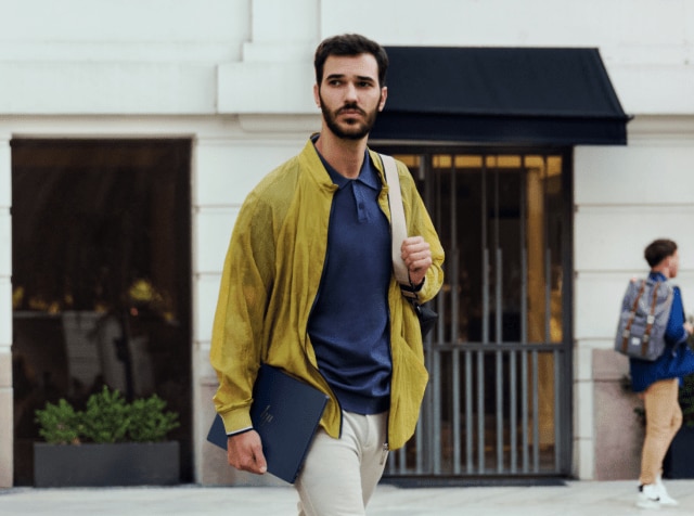 Man walking while carrying an HP laptop on his right hand