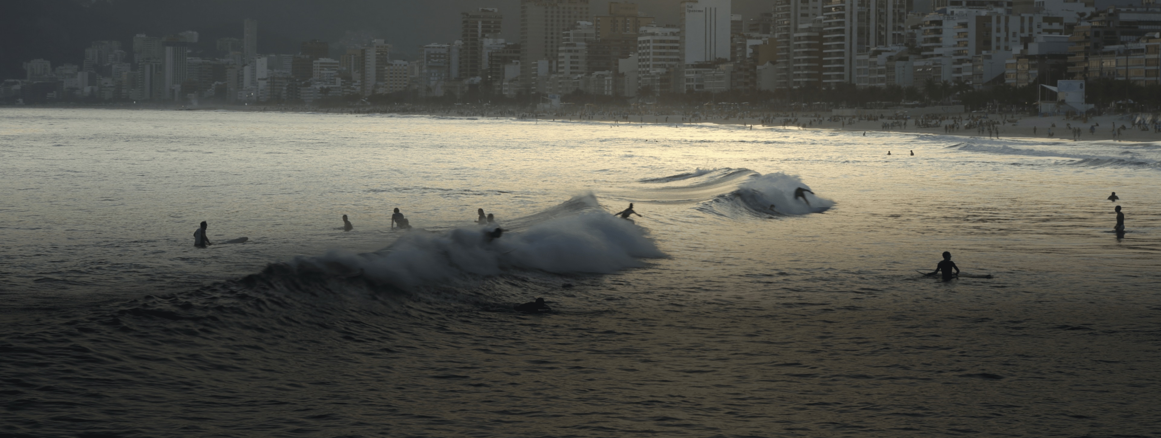People surfing in the ocean with a city skyline behind