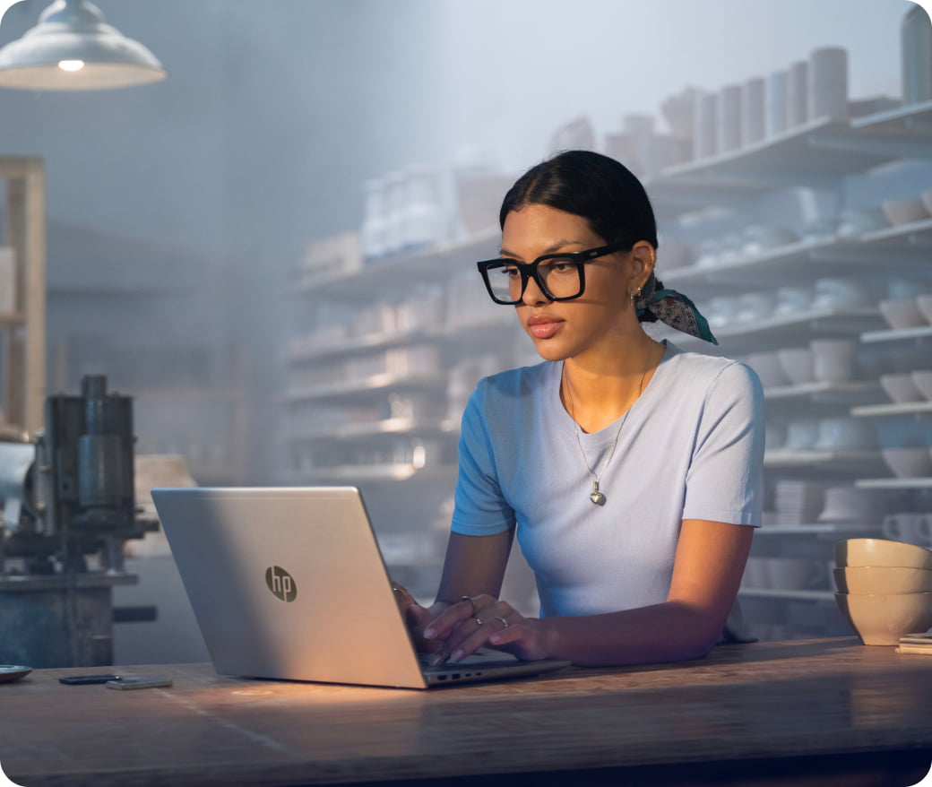 Une femme dans un atelier de poterie travaillant sur un ordinateur portable HP
