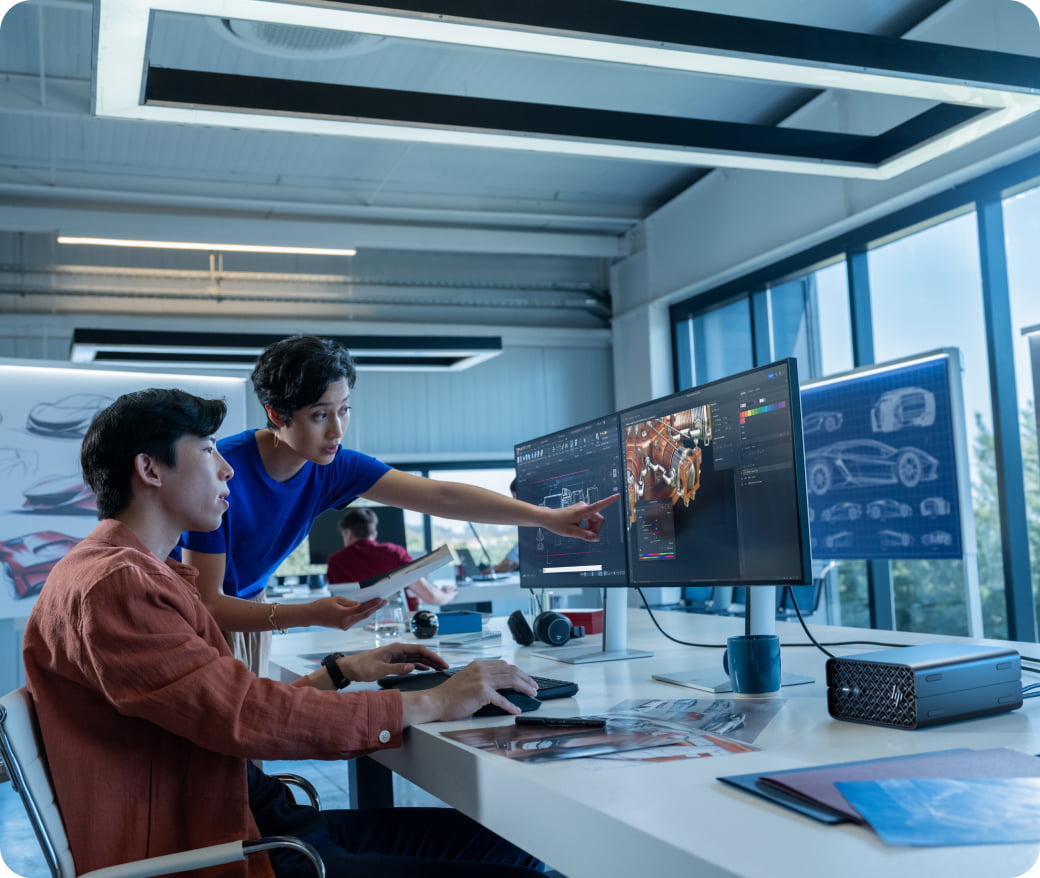 Un homme et une femme au bureau regardant deux écrans