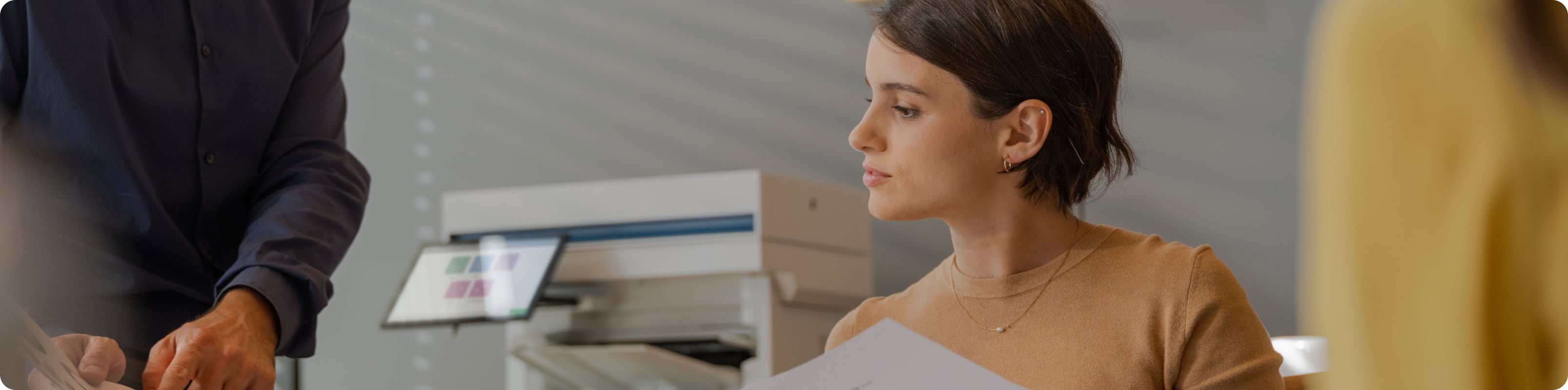 Scène de bureau avec une imprimante HP LaserJet Enterprise pendant que des professionnels examinent les impressions.