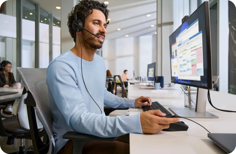 Seorang pria mengenakan headset HP Poly kabel dan bekerja menggunakan komputer.