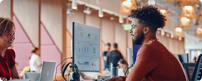Person looking at graphs displayed on a computer screen with headphones on the side. 