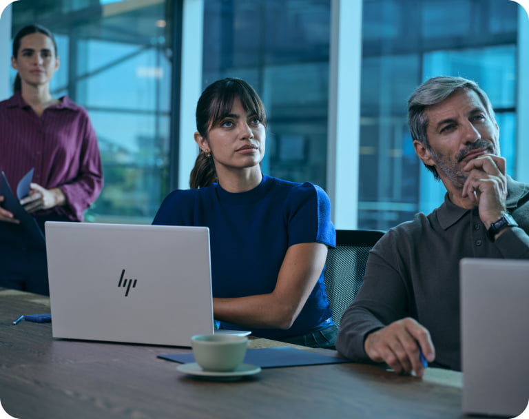 Team of professionals in modern office collaborating in shared workspace using HP laptops
