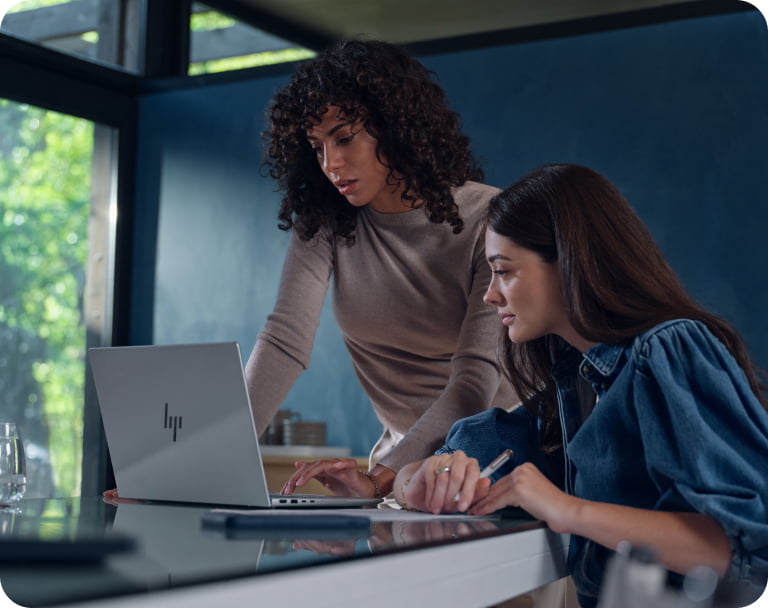 Team of professionals in modern office collaborating in shared workspace using HP laptops