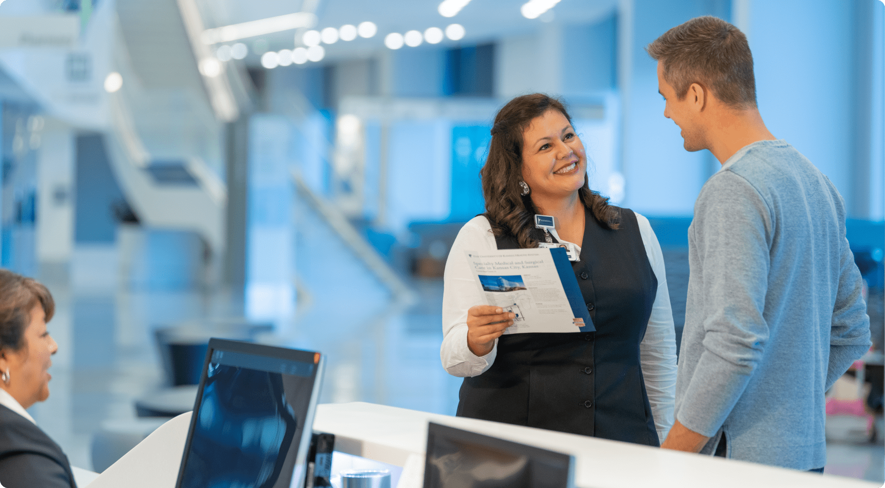 University of Kansas employees at reception desk discussing color documents