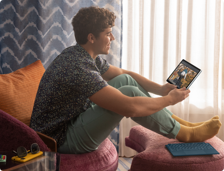 A young man in a living room watching at an HP Chromebook x2 11 inch in tablet mode