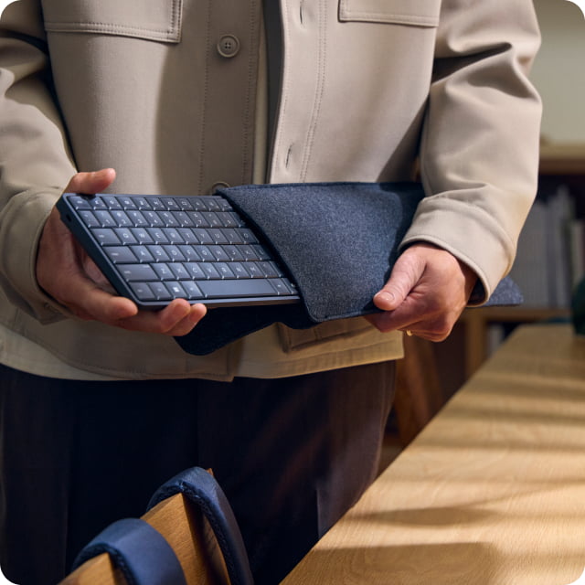 Man standing next to desk, pulling a HP EliteBoard G1a from protective sleeve