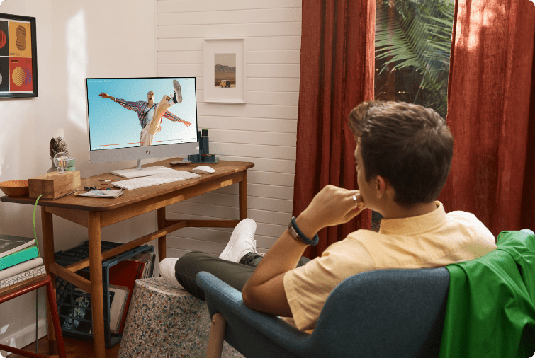 Man sitting on chair at home, watching a video on HP Pavilion All-in-One Desktop