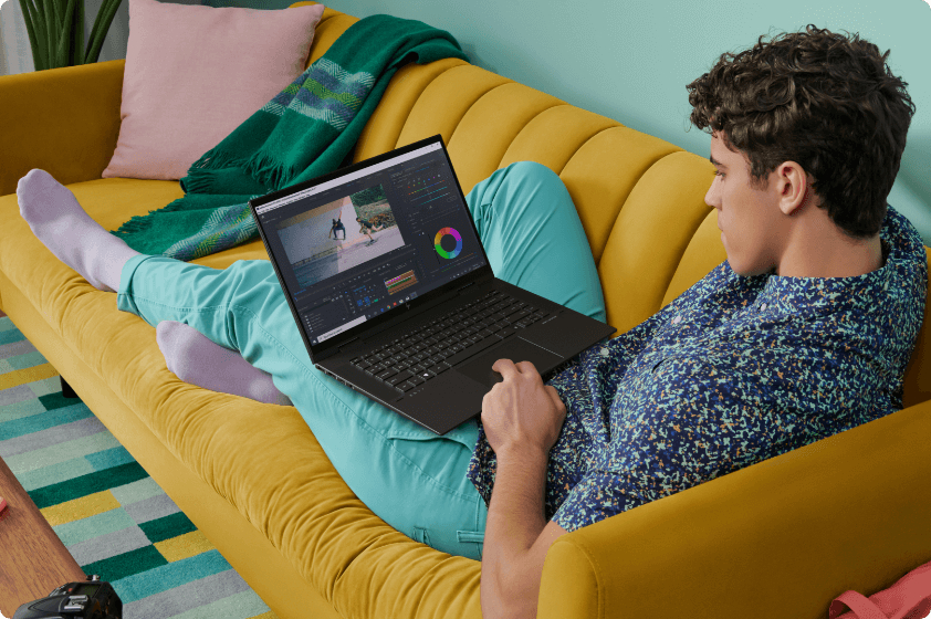 Young man sitting on a couch, editing a photograph using an HP ENVY x360 laptop