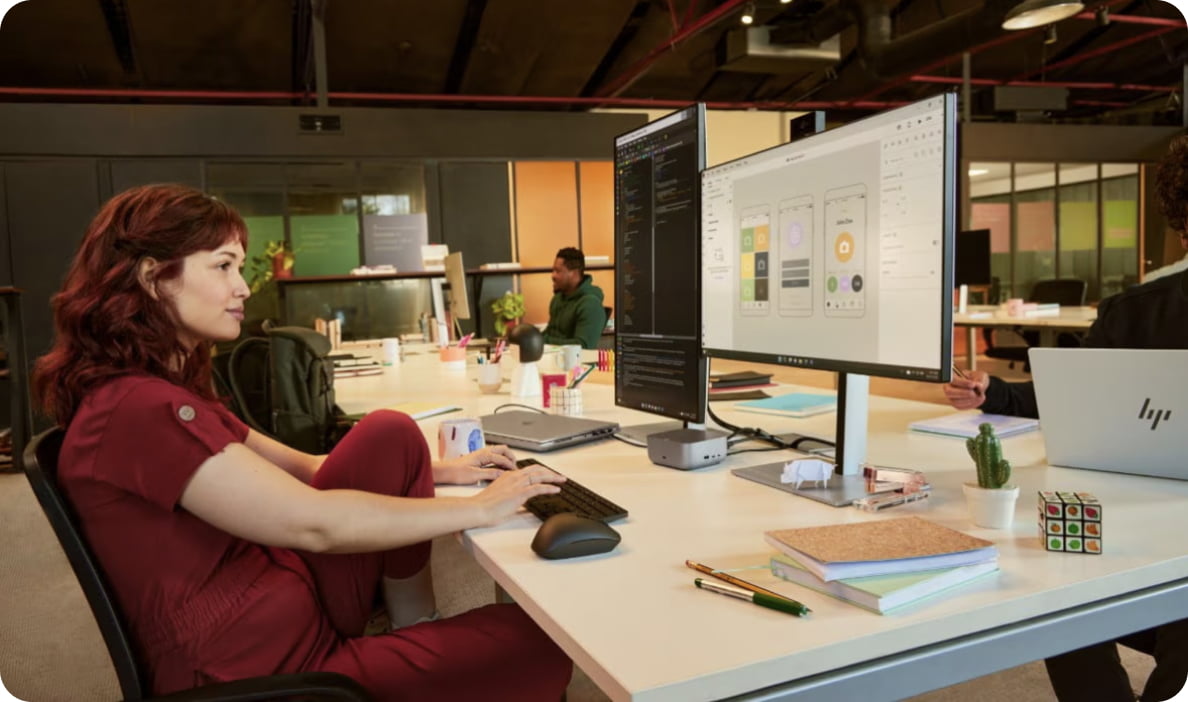 Person working casually on dual monitors connected to an HP dock. 