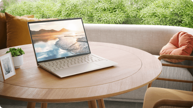 HP Pavilion Aero 13.3 inch laptop over a living room table, showing a nature theme wallpaper