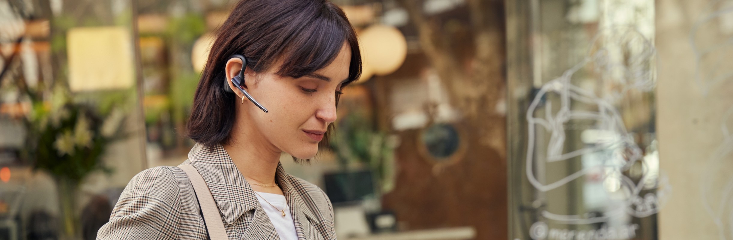 一位女士在户外正戴着蓝牙耳机