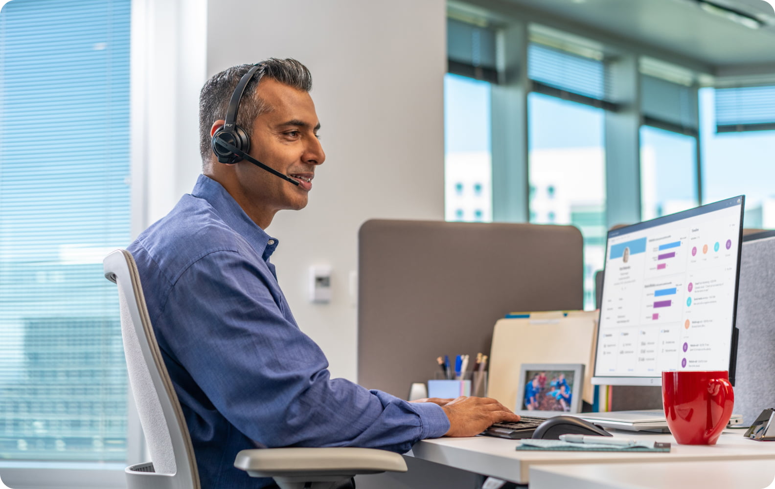 Man at desk wearing HP Poly Savi 8400 Office Series headset