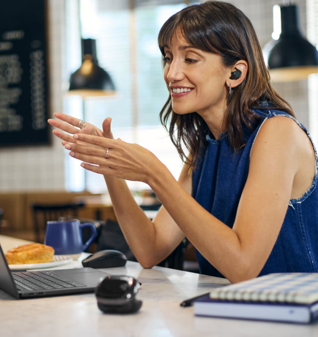 Eine Frau trägt Wirless-Earbuds in einem Café