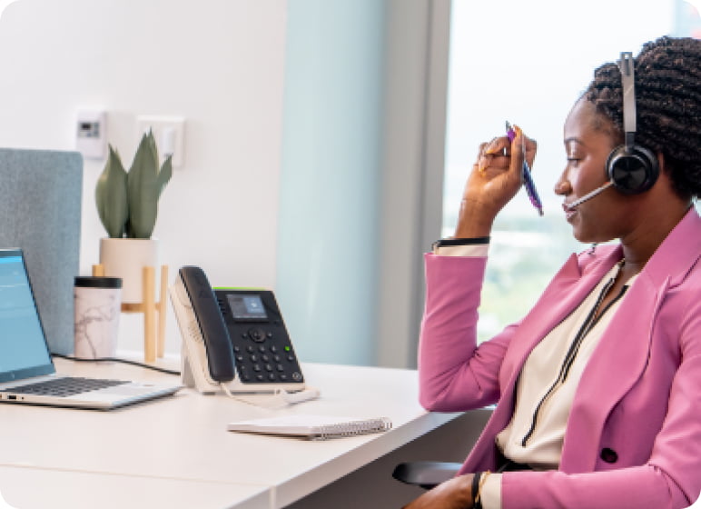 A woman wearing a headset and working on a laptop.