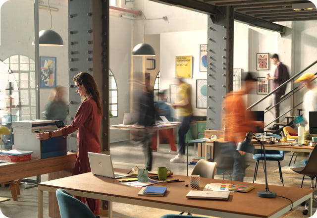 Small business team moving around creative office space using HP LaserJet and HP laptops