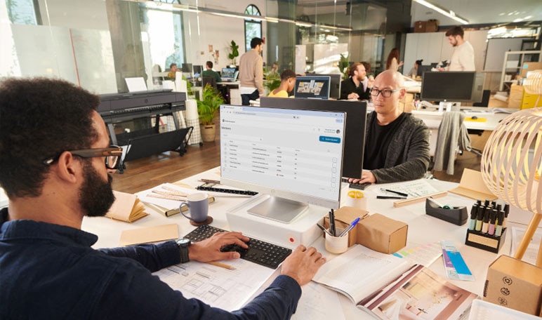 People working on construction project plans in an office with HP DesignJet printer in the background