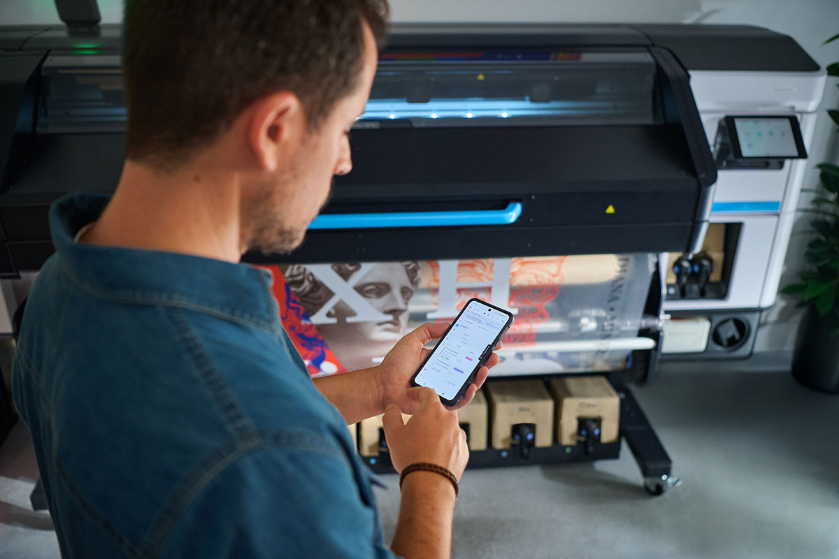 Person using a smartphone to manage print jobs on an HP Latex printer