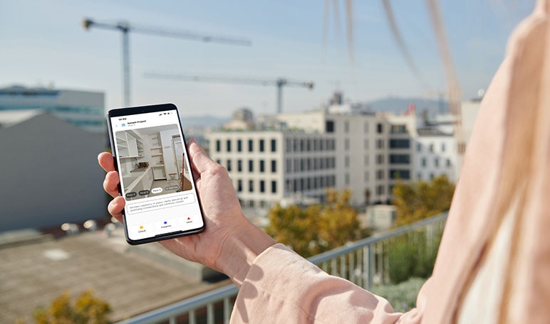 Person holding smartphone displaying interior design view on construction site
