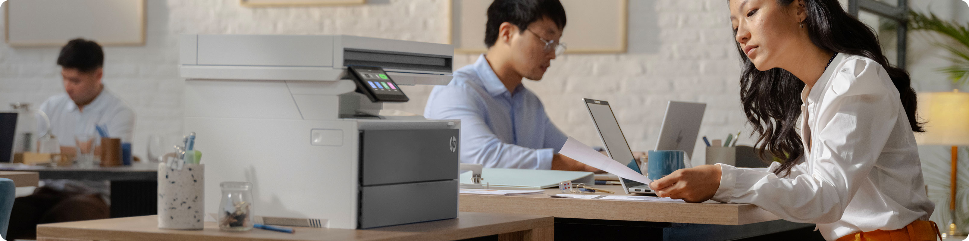 两人在 HP 打印机旁查看印刷资料