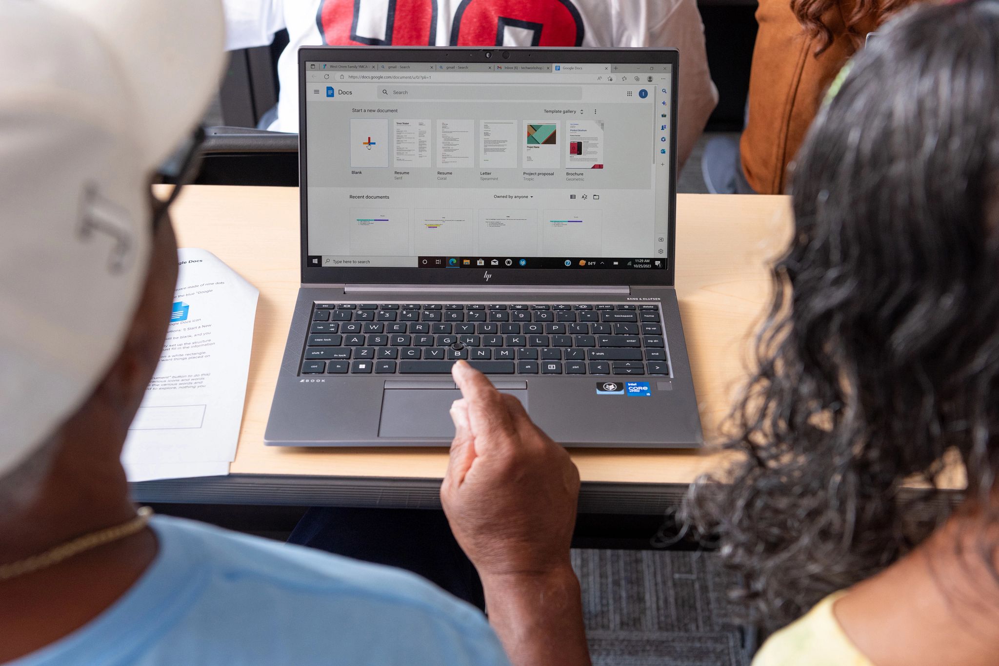 Man and woman looking at documents on a laptop screen.