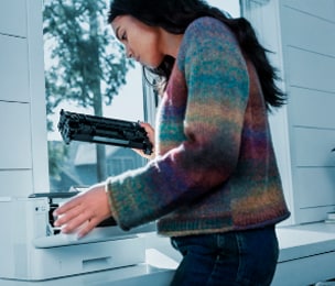 Eine junge Frau überprüft den Toner eines HP Druckers.