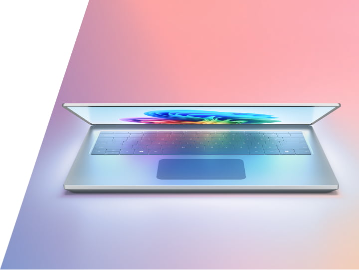 一台彩色屏幕部分打开的笔记本电脑，放置在渐变的粉红色和蓝色台面上。