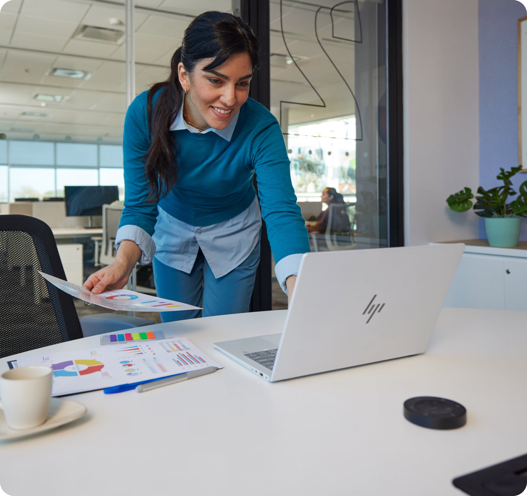 Man and woman in modern engineering office looking at car designs on an HP dual display and laptop with printed pages on the desk