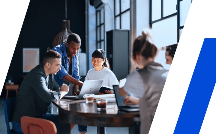 Group of coworkers at a round table in a sunny, modern office collaborating on content on an HP laptop