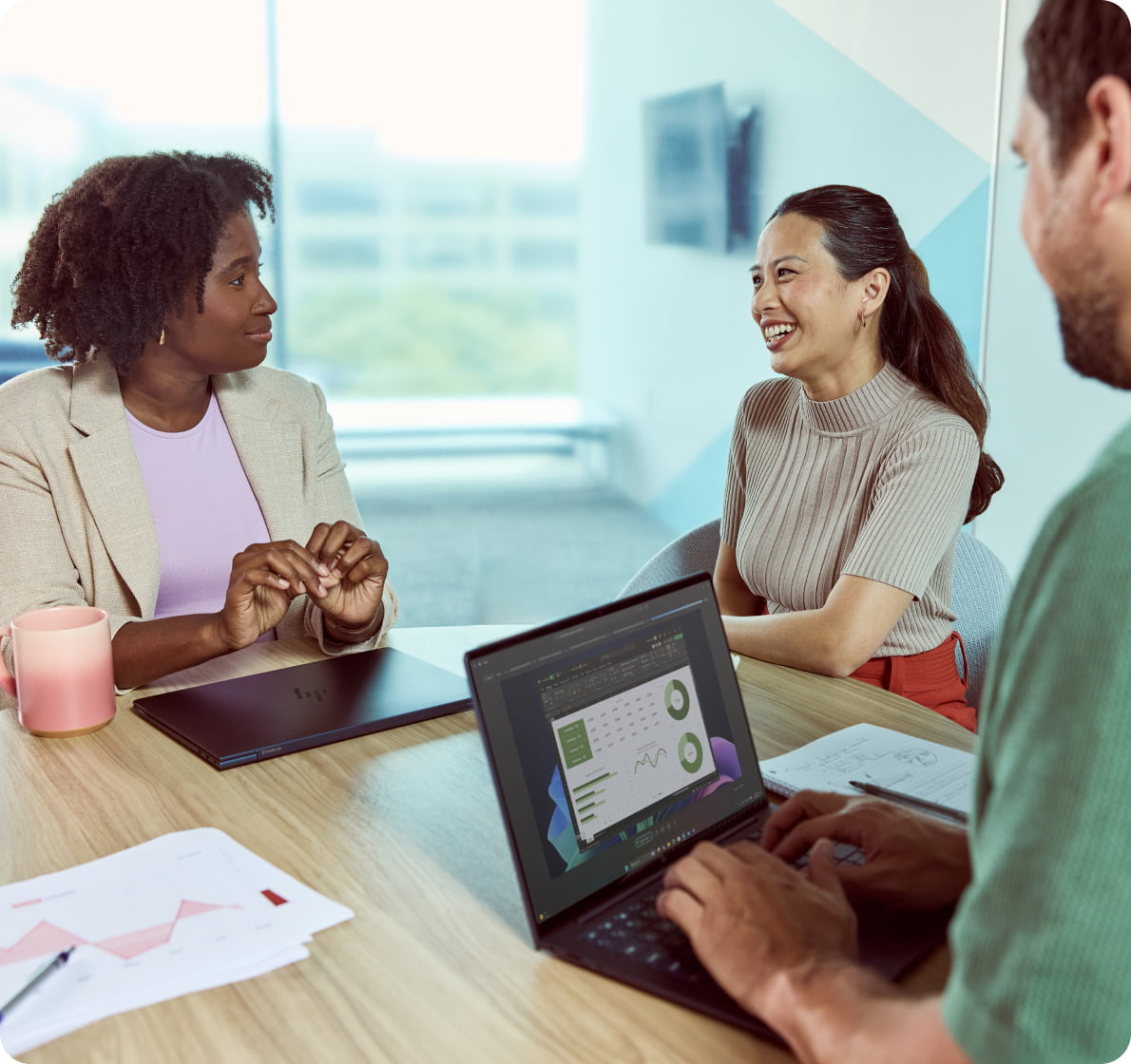 Team collaborating in a modern office with an HP laptop, discussing project data and strategy around a roundtable meeting