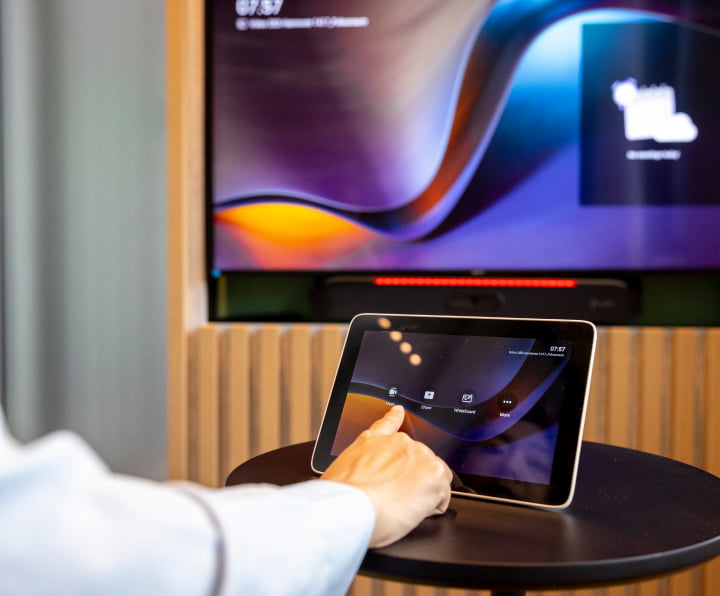 Close shot of professional using an HP Poly Collaboration touchscreen to control a video call