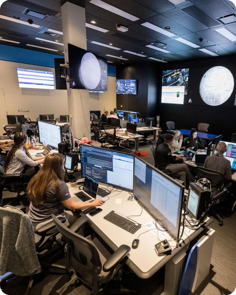 Individuals working on computers inside NASA mission control 