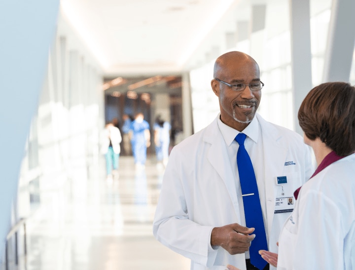 Male and female healthcare workers discussing patient care in hospital hallway