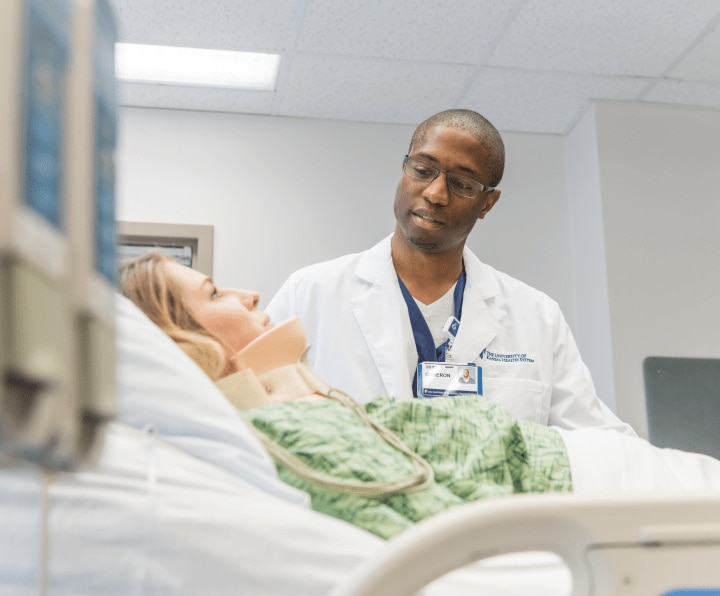Male healthcare worker standing at bedside of female patient