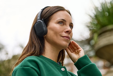 A person in a green shirt using poly wireless headphones outdoor