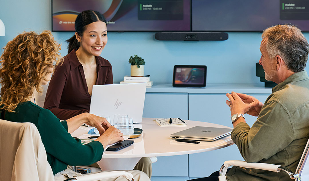 Two coworkers collaborate at a desk with a laptop.