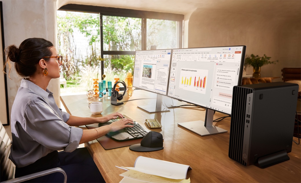 Uma pessoa sentada à mesa com um computador desktop SFF 800 G9, trabalhando, cercada por materiais de escritório.
