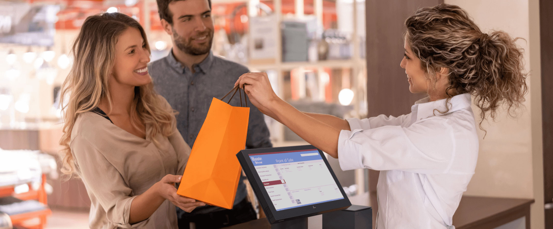 一對夫婦從收銀員手中接過購物袋,收銀台用的就是 HP Engage POS 系統
