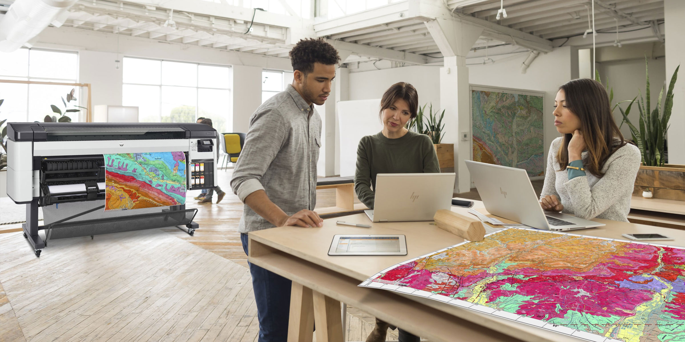 Personas trabajando con impresiones al lado de un plotter HP DesignJet