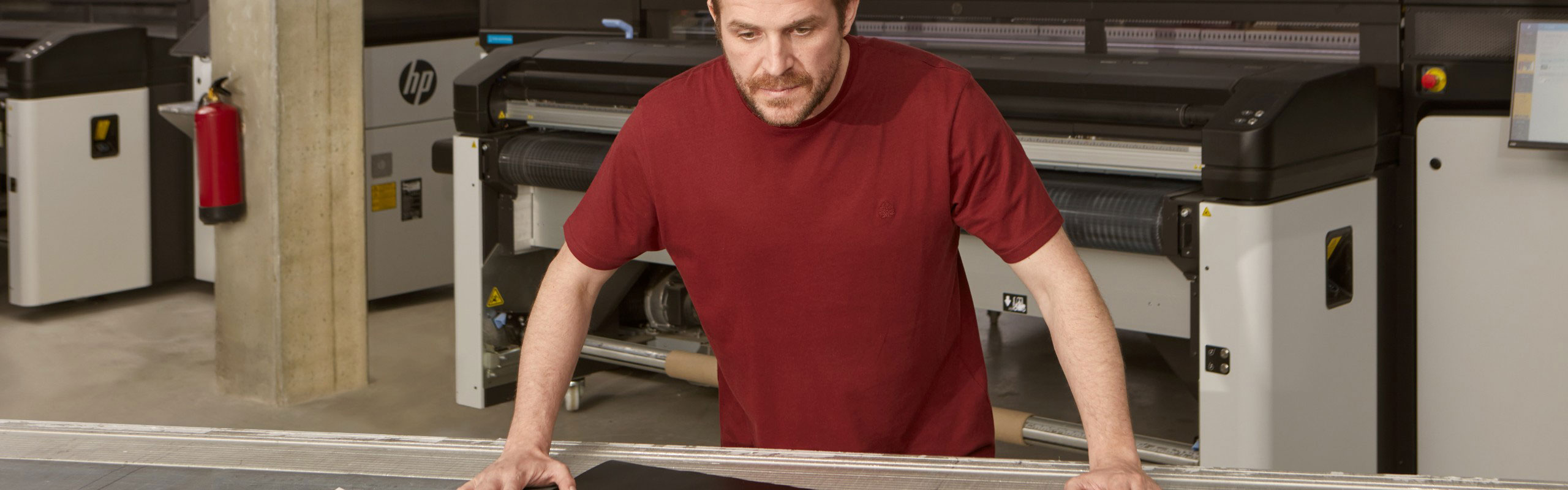 Person next to a work table in front of an HP Latex R series printer