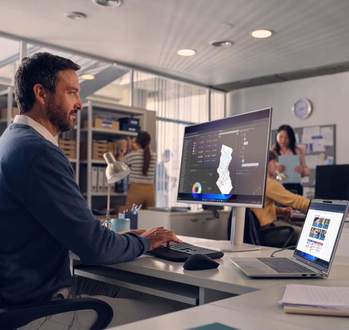 Man in office works on HP laptop and monitor
